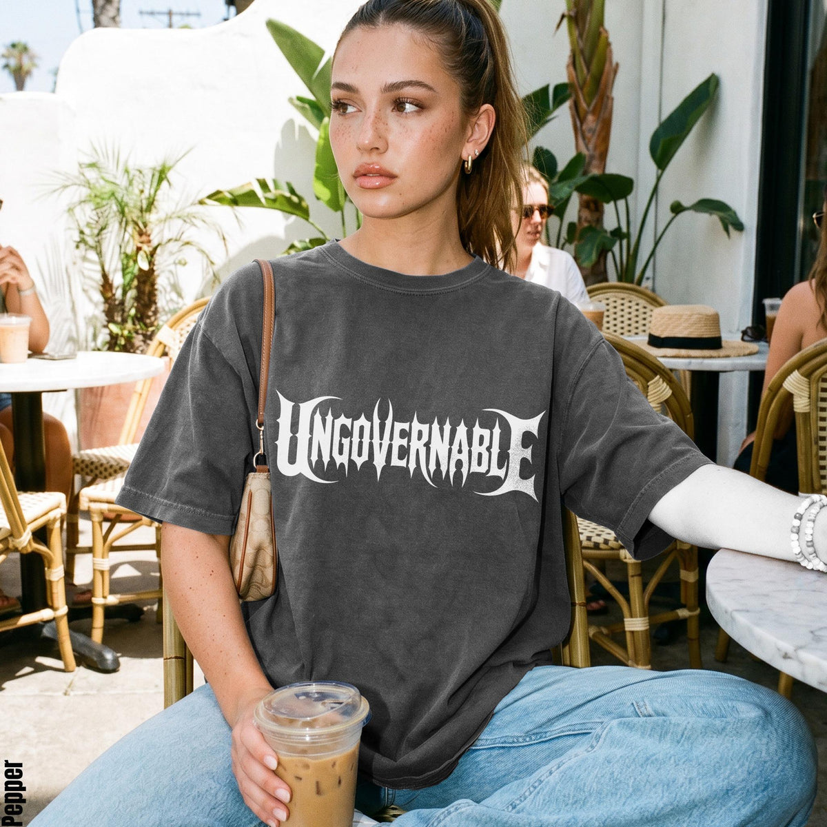 Young woman wearing a dark gray t-shirt with white &amp;quot;UNGOVERNABLE&amp;quot; text and light blue jeans.