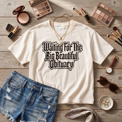 Cream t-shirt with black gothic text &amp;quot;Waiting For The Big Beautiful Obituary&amp;quot;.
