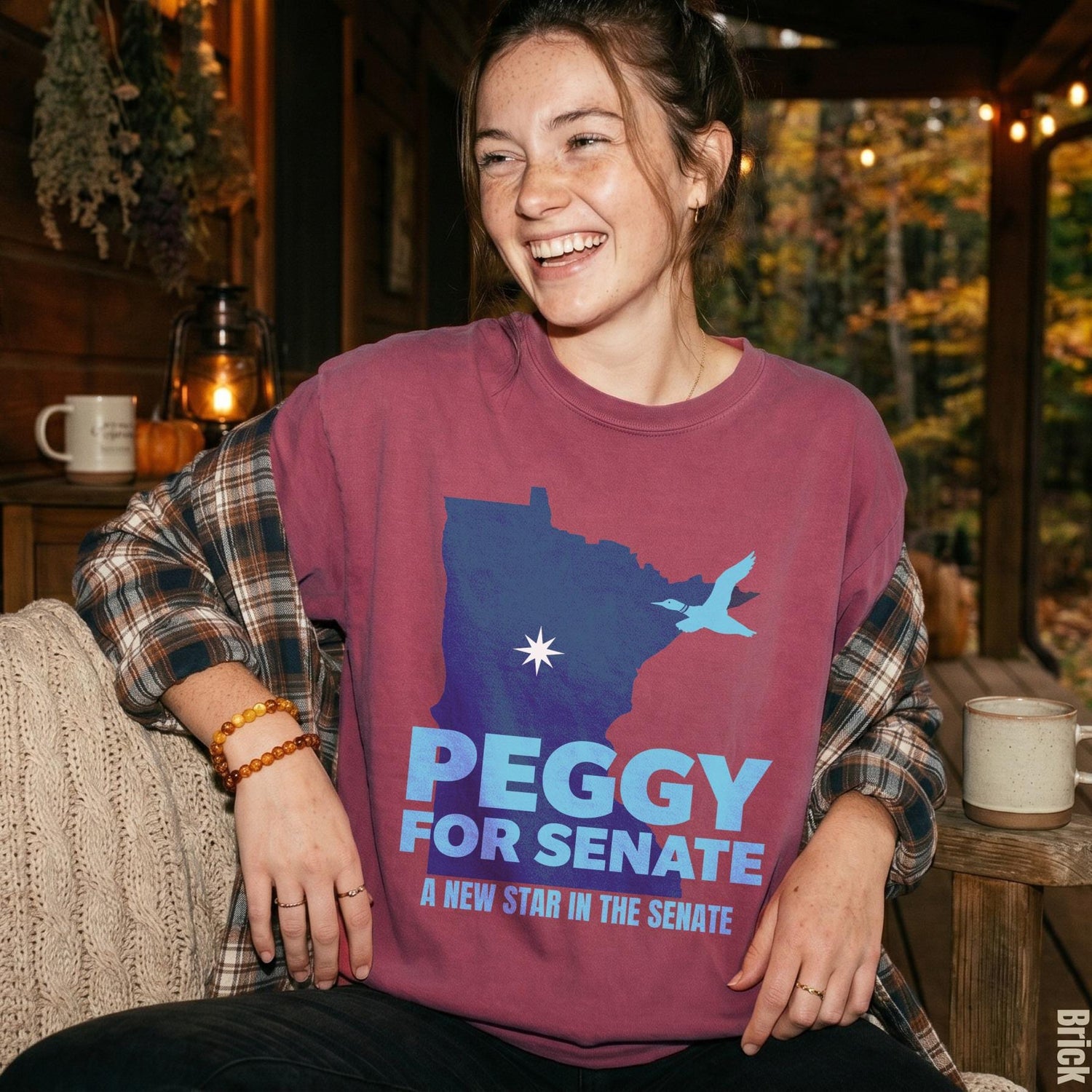 Burgundy shirt with Minnesota outline, bird, and text &amp;quot;Peggy for Senate&amp;quot;.