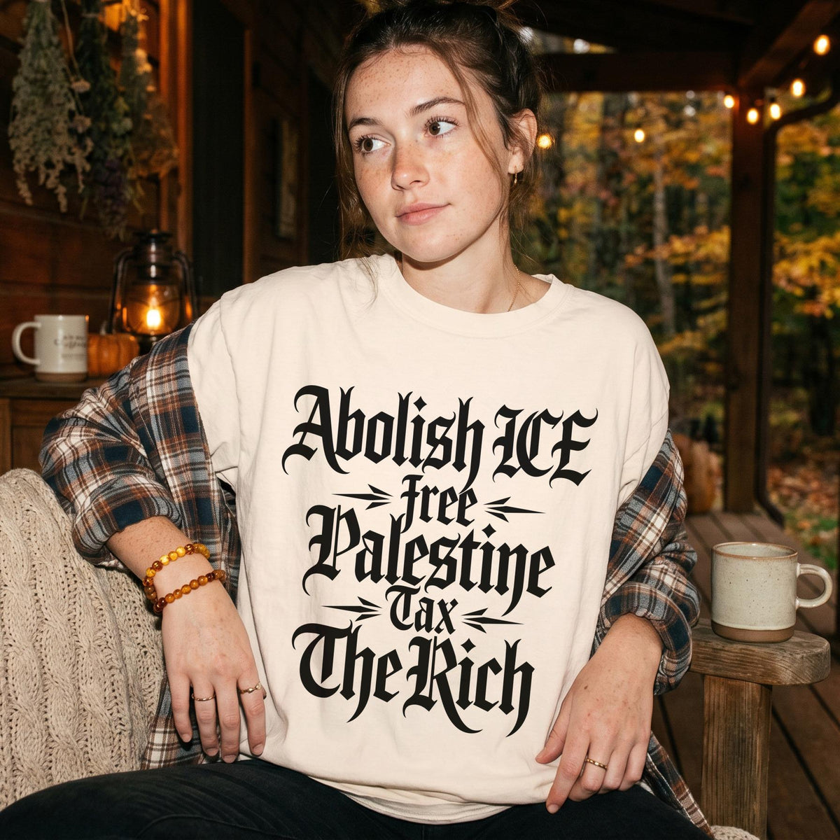 Woman wearing cream shirt with text &amp;quot;Abolish ICE free Palestine Tax The Rich&amp;quot;.