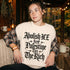 Woman wearing cream shirt with text "Abolish ICE free Palestine Tax The Rich".