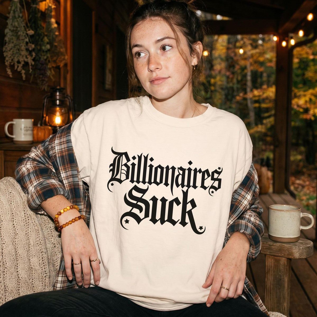 Cream t-shirt with black gothic text &amp;quot;Billionaires Suck&amp;quot; worn by a young woman.