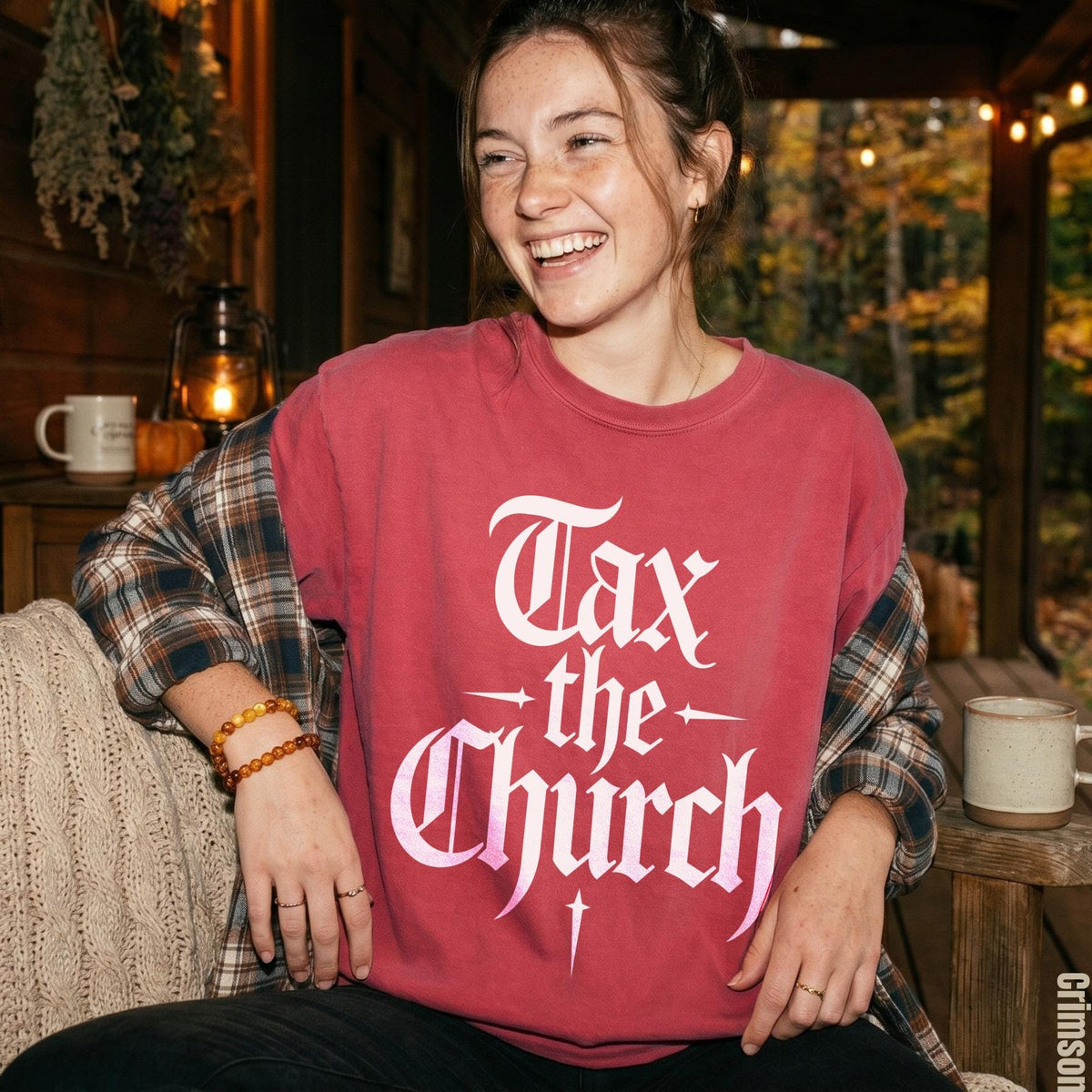 Woman wearing a red shirt with &amp;quot;Tax the Church&amp;quot; graphic and flannel.