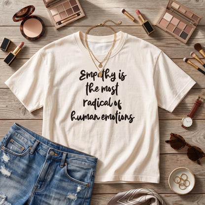 Cream t-shirt with text &amp;quot;Empathy is the most radical of human emotions,&amp;quot; denim shorts, and accessories.
