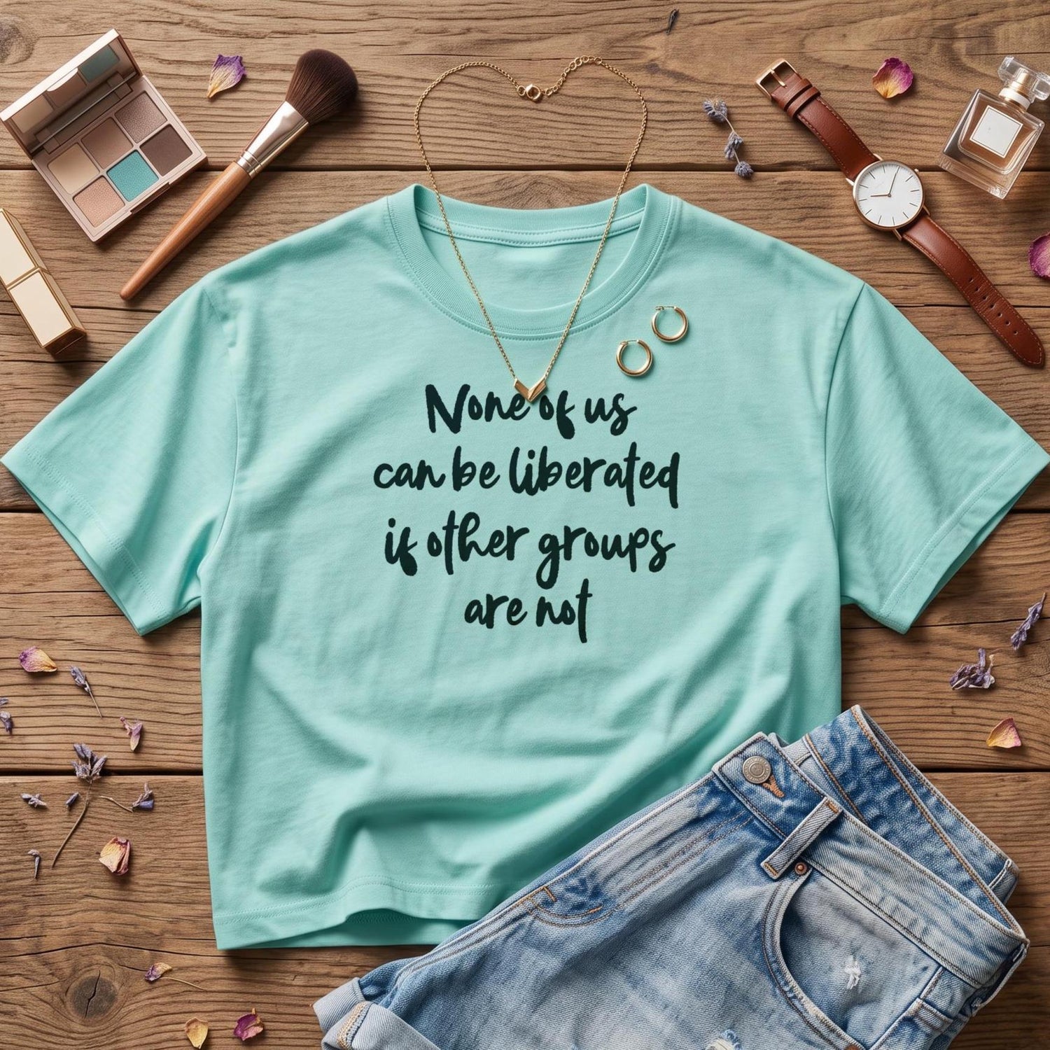 Teal t-shirt with black text &amp;quot;None of us can be liberated if other groups are not.&amp;quot;