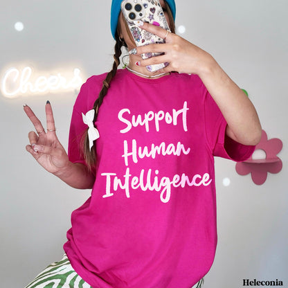 Pink t-shirt with &amp;quot;Support Human Intelligence&amp;quot; text, worn by a person holding a phone.