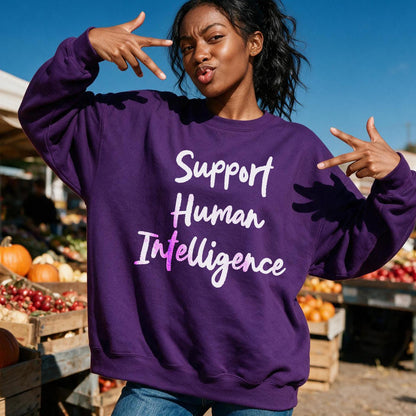 Woman in purple sweatshirt with &amp;quot;Support Human Intelligence&amp;quot; text, making peace signs outdoors.