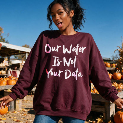 Woman wearing maroon sweatshirt with text &amp;quot;Our Water Is Not Your Data&amp;quot; at pumpkin patch.