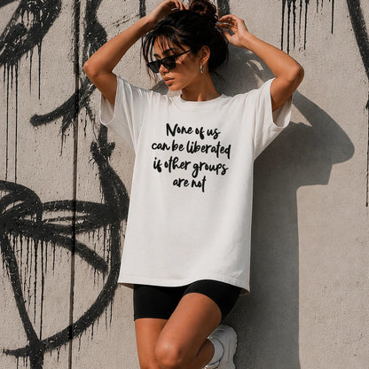 Woman in white t-shirt with text: None of us can be liberated if other groups are not.