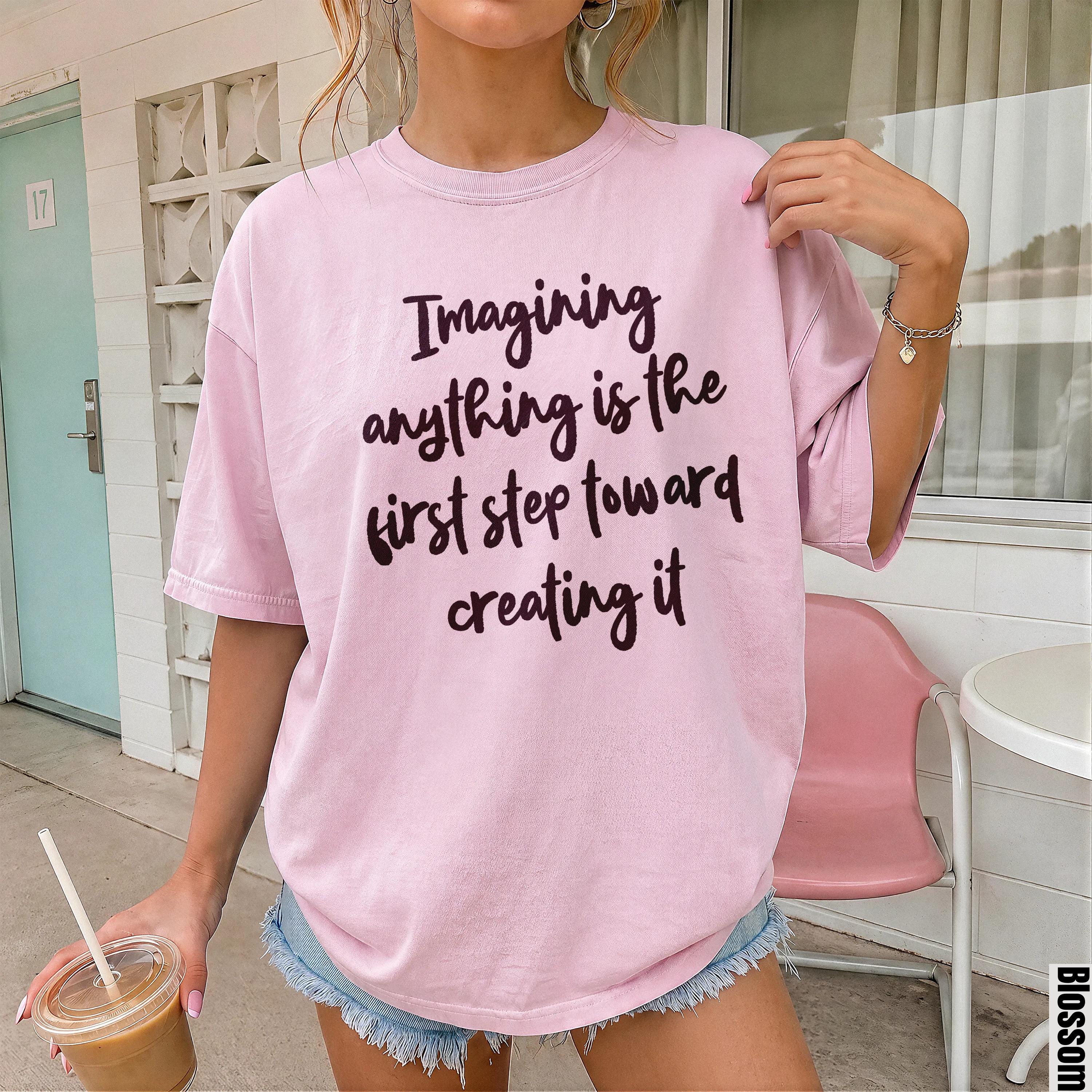 Pink t-shirt with dark text reading &amp;quot;Imagining anything is the first step toward creating it&amp;quot;.