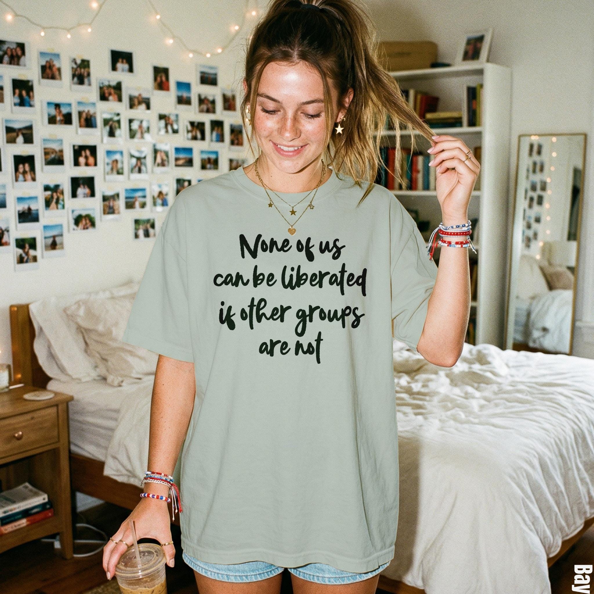 Light green t-shirt with text: &amp;quot;None of us can be liberated if other groups are not&amp;quot;.
