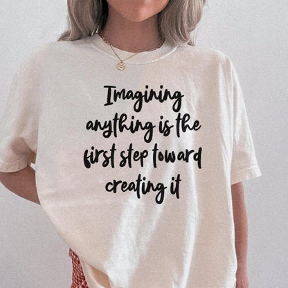 Cream t-shirt with black text reading &amp;quot;Imagining anything is the first step toward creating it&amp;quot;.
