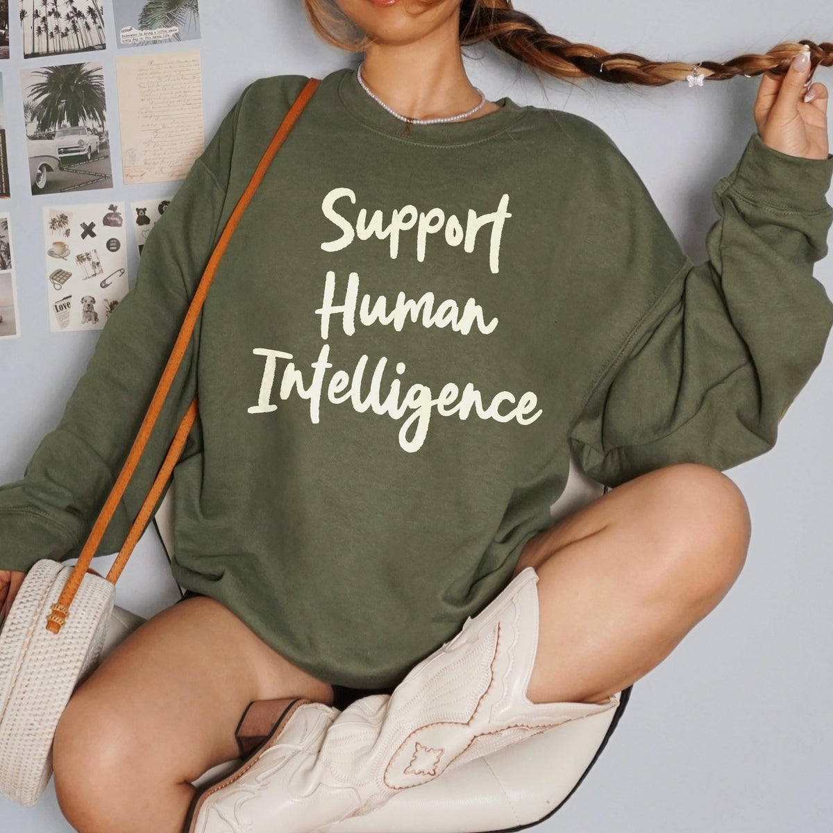 Green sweatshirt with &amp;quot;Support Human Intelligence&amp;quot; text, worn by a seated person.