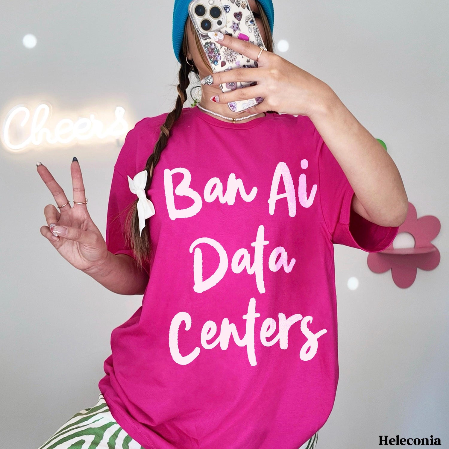 Pink t-shirt with white text &amp;quot;Ban Ai Data Centers,&amp;quot; woman posing with phone.