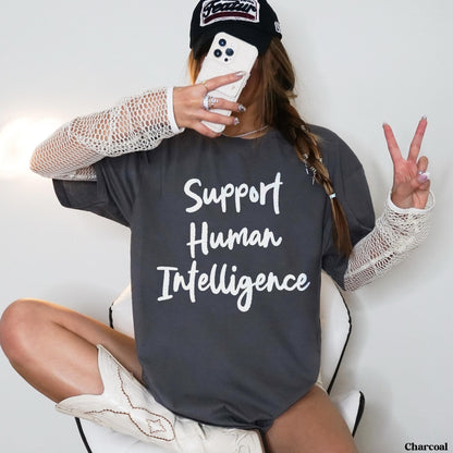 Charcoal t-shirt with &amp;quot;Support Human Intelligence&amp;quot; text, worn by a woman holding a phone and making peace sign.
