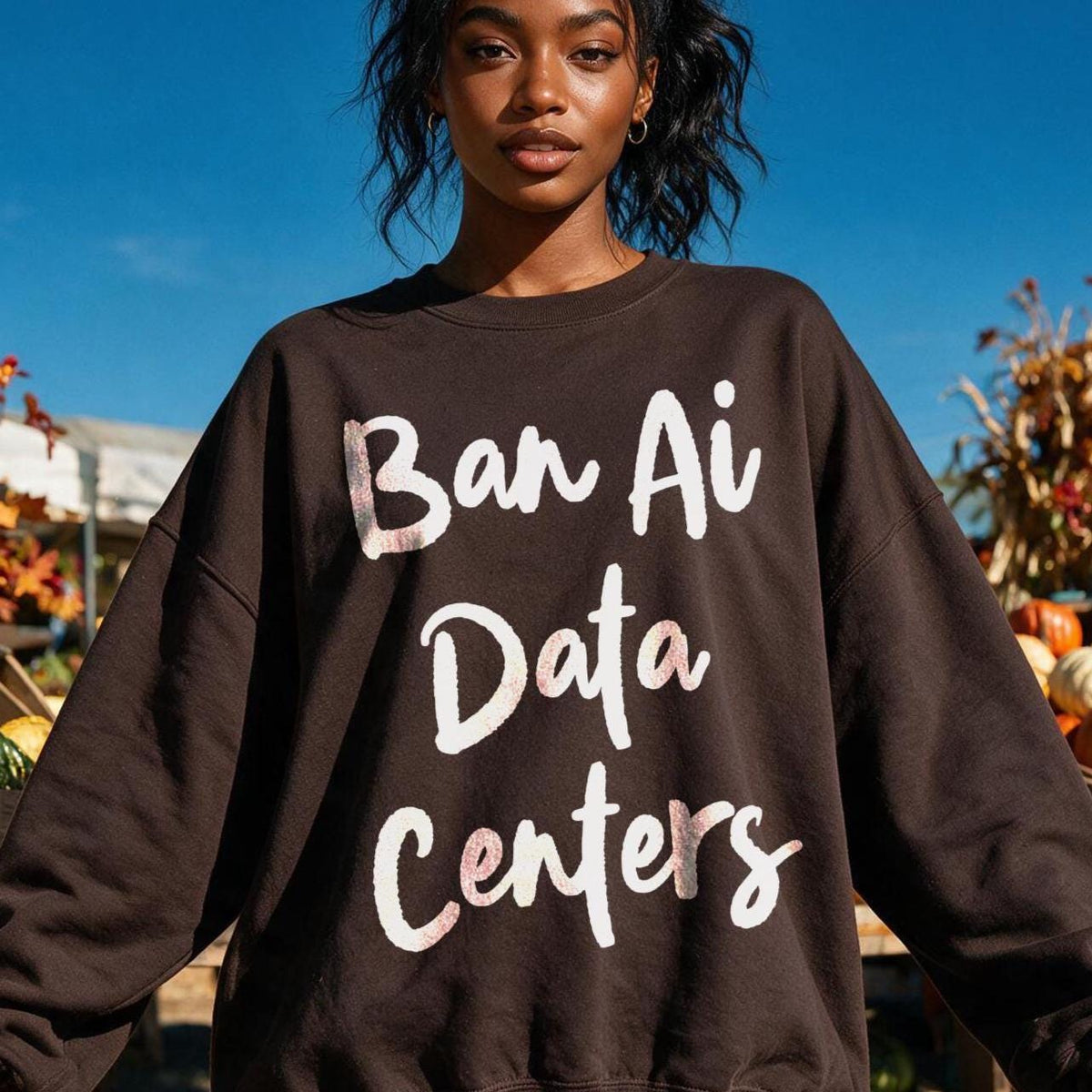 Woman wearing brown sweatshirt with &amp;quot;Ban Ai Data Centers&amp;quot; text, outdoors with pumpkins.
