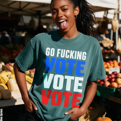 Woman wearing a teal t-shirt with &amp;quot;GO FUCKING VOTE&amp;quot; repeated in colored text.