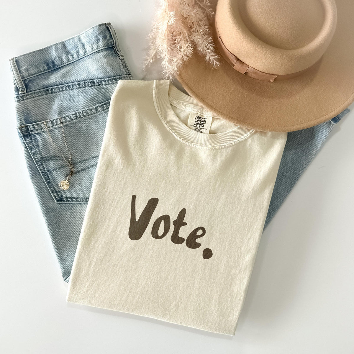 Light beige t-shirt with &amp;quot;Vote.&amp;quot; text, denim jeans, and a hat.