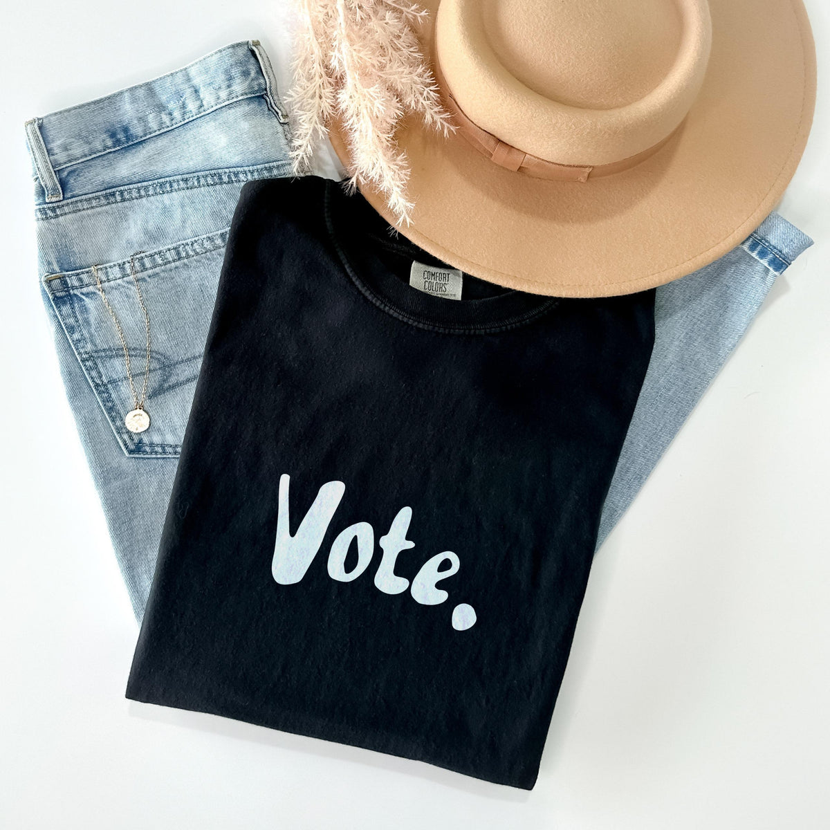 Black t-shirt with &amp;quot;Vote.&amp;quot; text, light wash jeans, necklace, and tan hat.