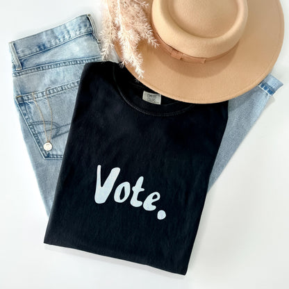 Black t-shirt with &amp;quot;Vote.&amp;quot; text, light wash jeans, necklace, and tan hat.