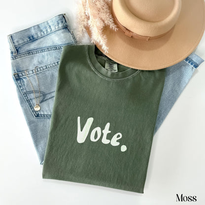 Green t-shirt with &amp;quot;Vote&amp;quot; text, light wash jeans, hat, and necklace.