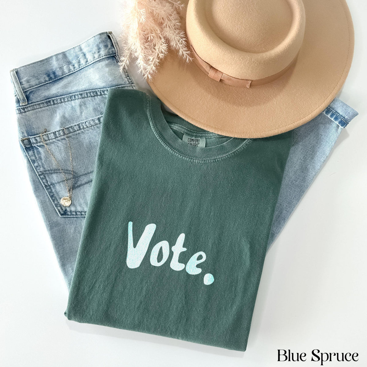 Teal t-shirt with &amp;quot;Vote.&amp;quot; text, laid out with jeans, hat, and necklace.