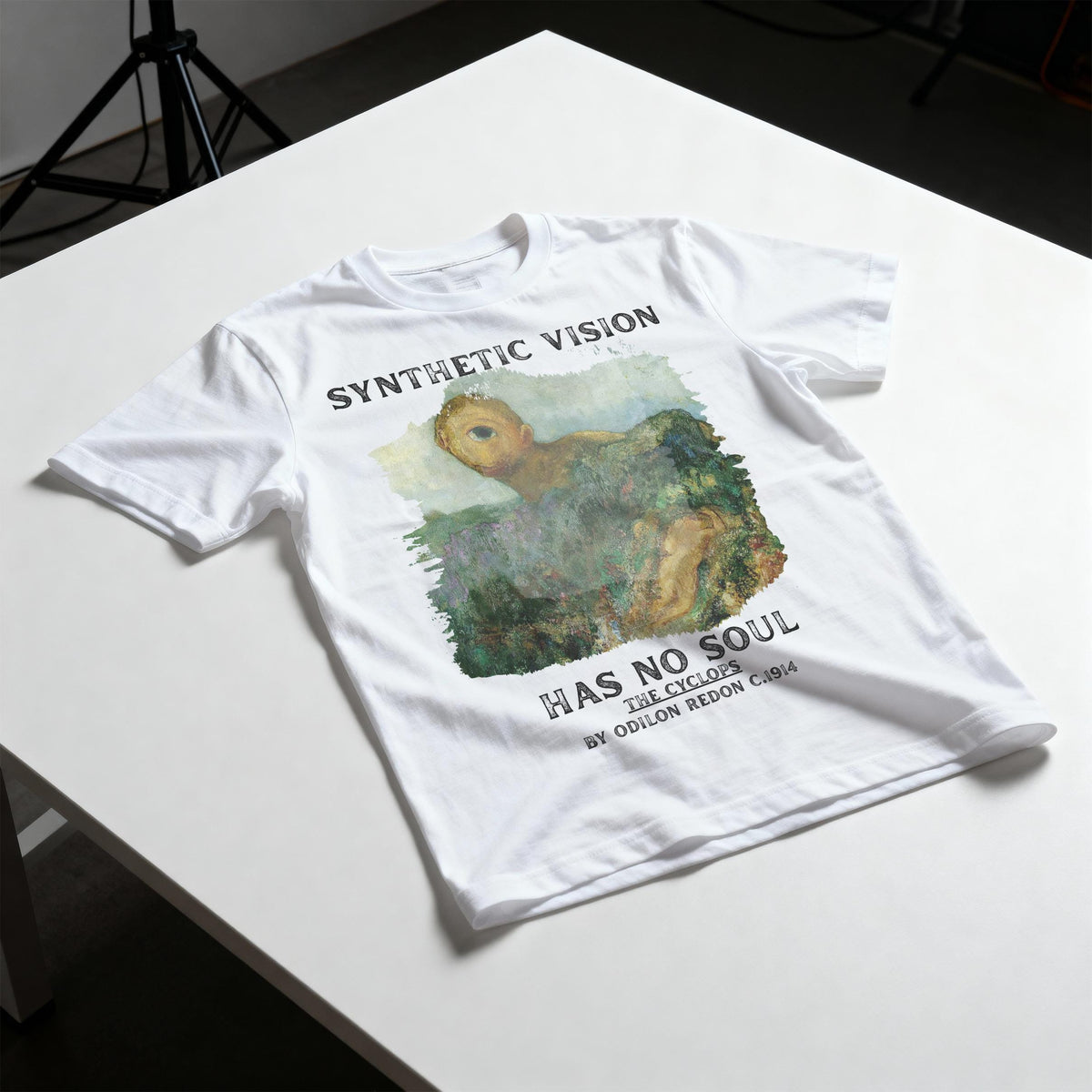 White t-shirt with &amp;quot;SYNTHETIC VISION&amp;quot; and &amp;quot;THE CYCLOPS&amp;quot; art by Odilon Redon.