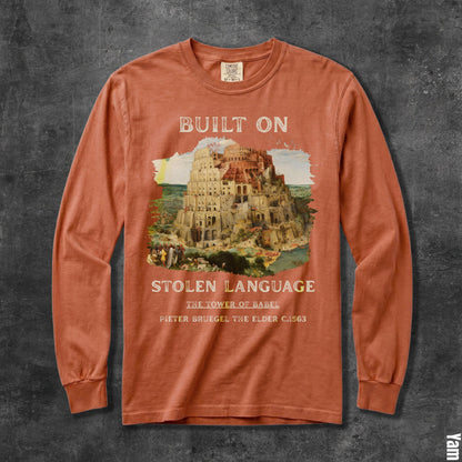 Long sleeve orange shirt with &amp;quot;Built On Stolen Language&amp;quot; and Tower of Babel artwork.