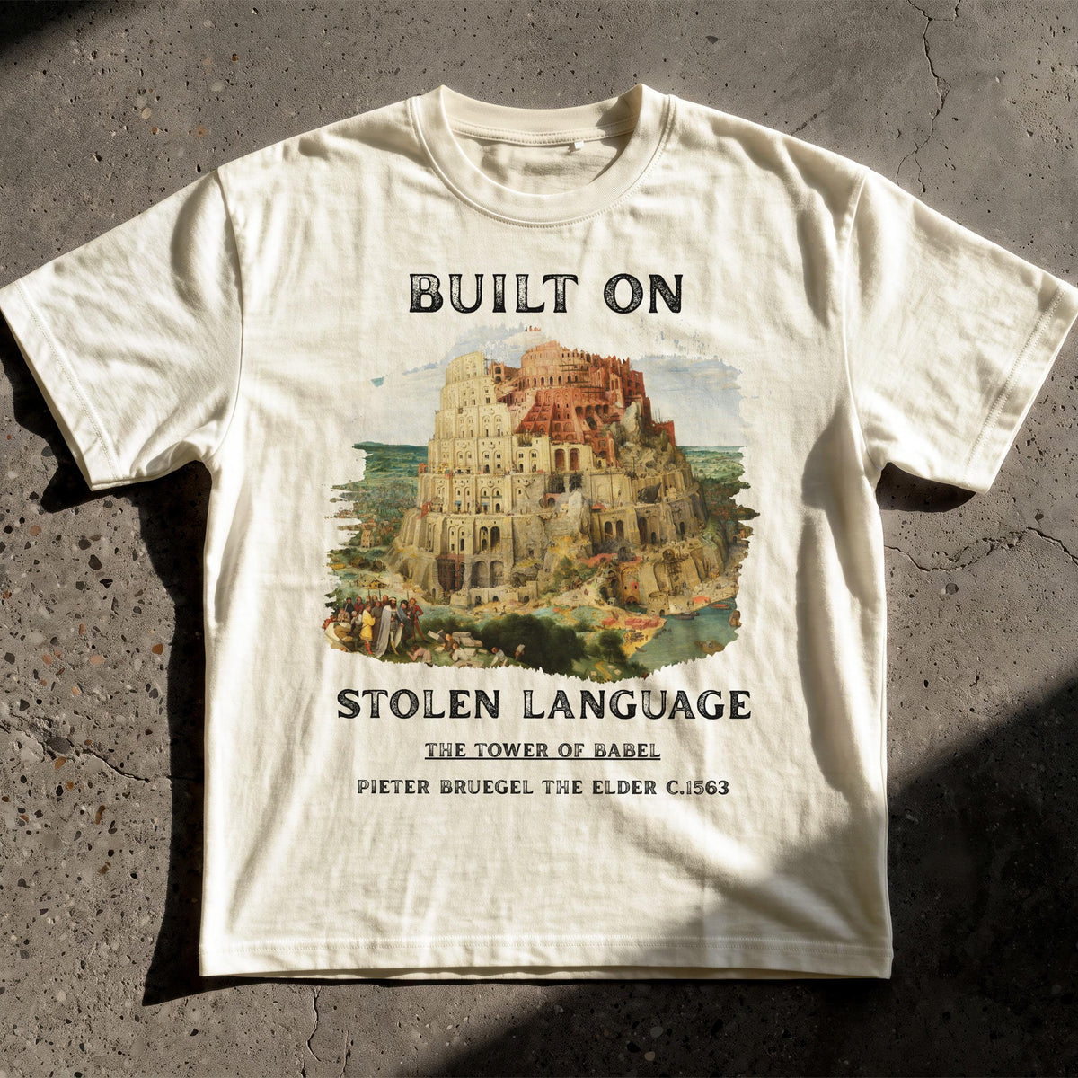 Cream t-shirt with &amp;quot;BUILT ON STOLEN LANGUAGE THE TOWER OF BABEL&amp;quot; text.