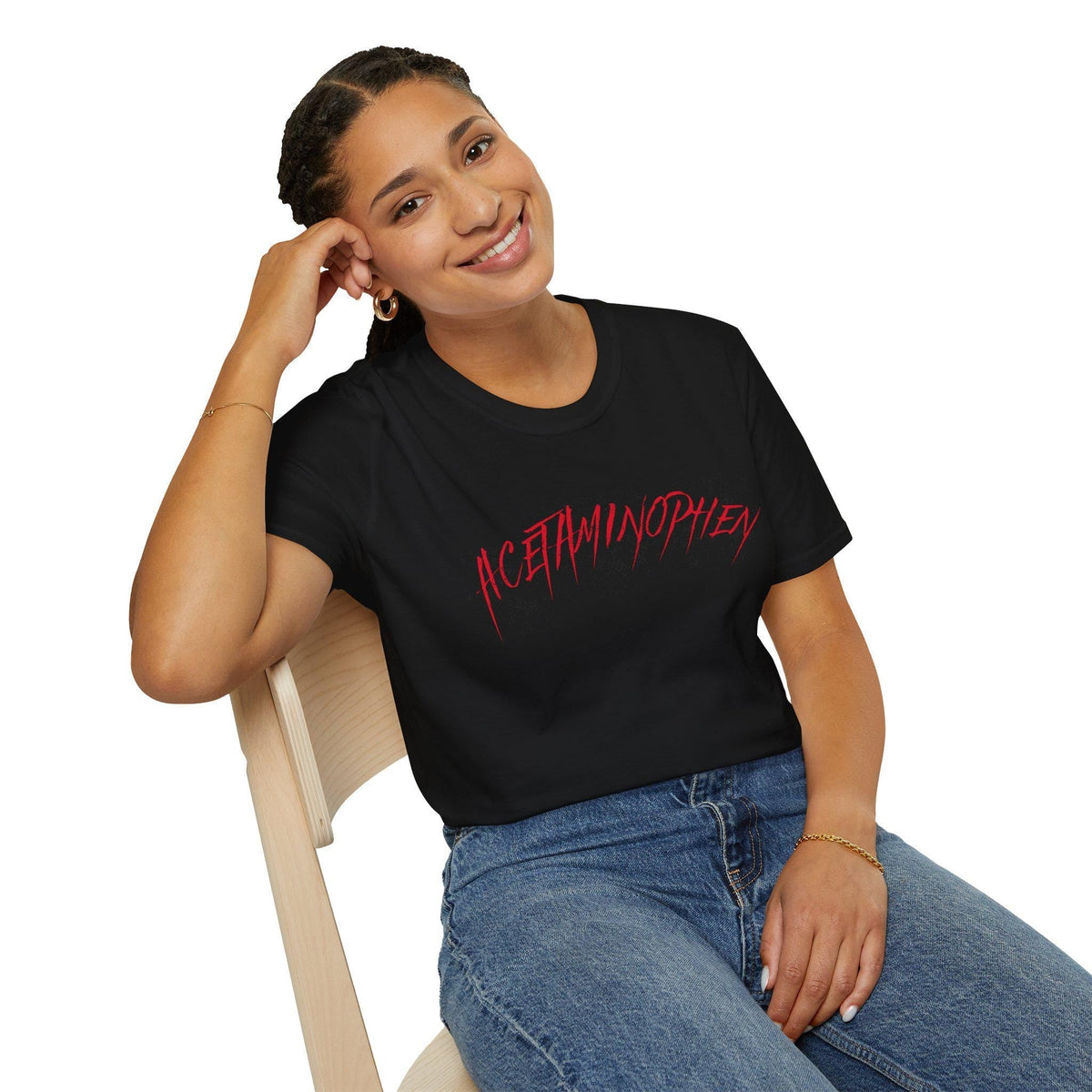 May include: Black t-shirt with the word &amp;quot;ACETAMINOPHEN&amp;quot; in red, stylized text. The shirt is worn by a person sitting in a wooden chair, wearing blue jeans and a gold bracelet. The person is smiling.