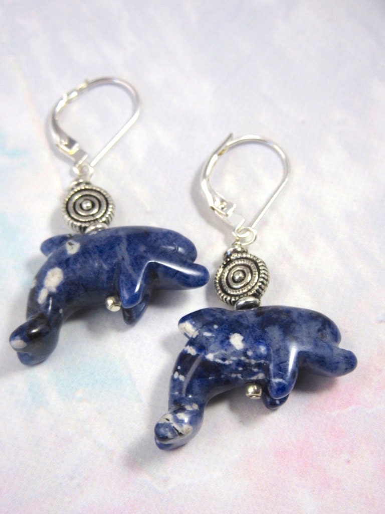 Close-up view of carved stone dolphins in Sodalite, showcasing the delicate craftsmanship of blue dolphin jewelry, ideal for ocean lovers.