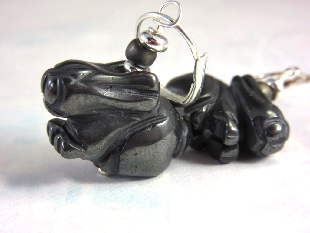 Close-up of Black Rabbit Carved Stone Bunny Earrings – White Rabbit Animal Jewelry, featuring black rabbit shapes with silver hooks and a round black bead above each. The light, blurred background highlights these unique animal-themed earrings.