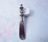 The Handcrafted Dip Spreader Knife – Glass Beads, Modern Entertaining features a silver-detailed glass bead handle and rests on white stone against a pastel background—an ideal accent for stylish gatherings.