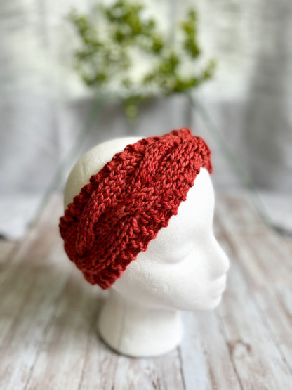 A mannequin head displays an orange hand-dyed, Virginia-raised merino cabled ear warmer