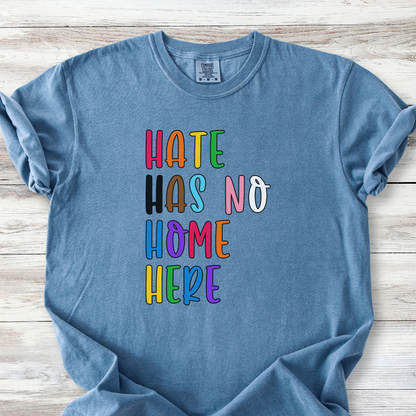 t-shirt with hand-lettered text reading Hate Has No Home Here in inclusive rainbow colors. Available on both the Comfort Colors 1717 tee or the Bella Canvas V-Neck Tee