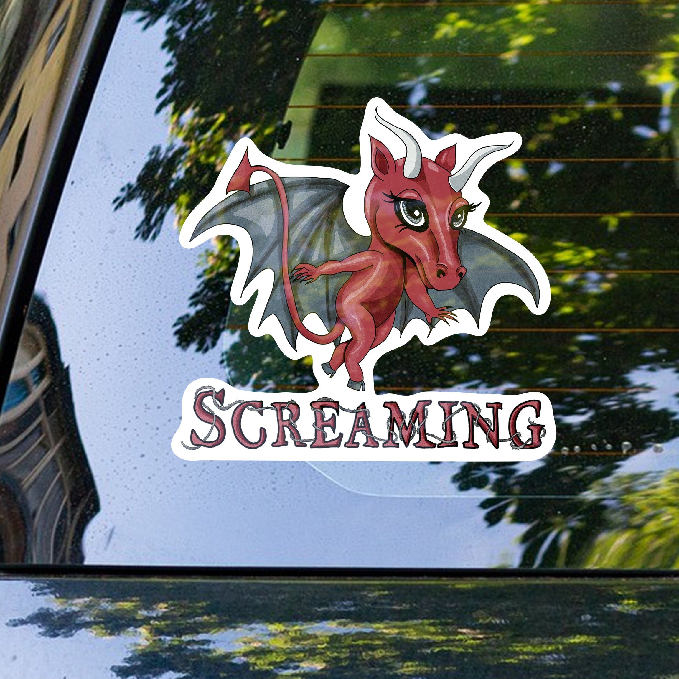 Jersey Devil cryptid sticker on the rear window of a car with trees reflected behind
