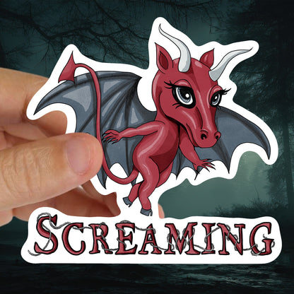 Hand holding the Jersey Devil sticker against a dark misty forest background