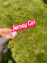 A hand holding a pink sticker with the text &