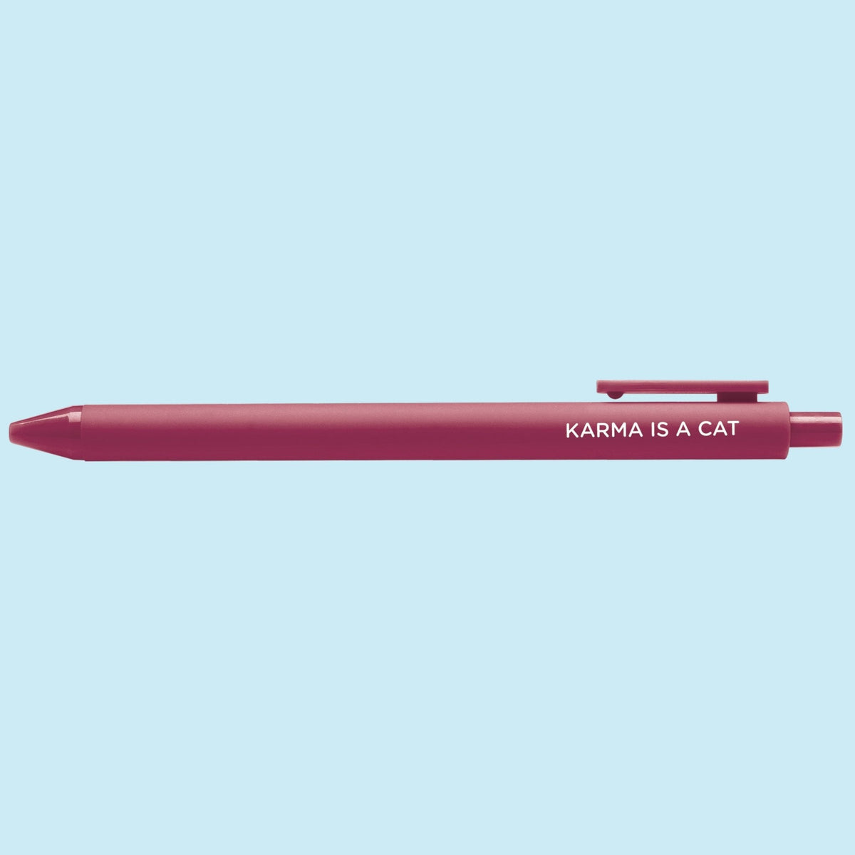 Karma is a Cat pen flat lay — maroon cat lover gel pen on a light blue background by indie artist MangoIllustrated