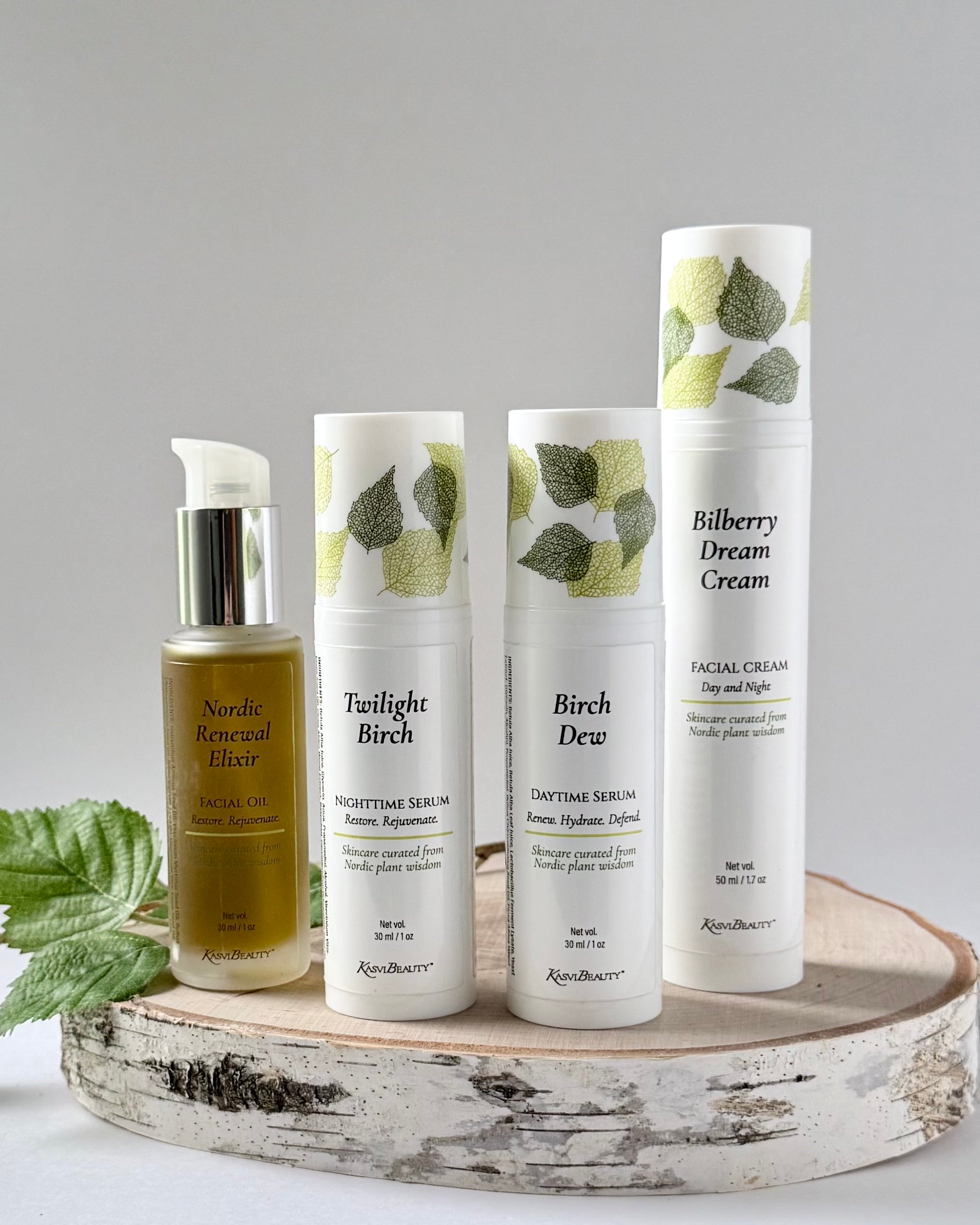 Set of four skincare products on a wooden tray with a gray background. Kasvi Beauty The Ritual Kit with daytime and nighttime serum, face oil, face cream moisturizer.