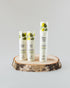 Three white skincare bottles from Kasvi Beauty displayed on a rustic wood slice against a light gray background. The bottles feature green leaf illustrations and labels for &