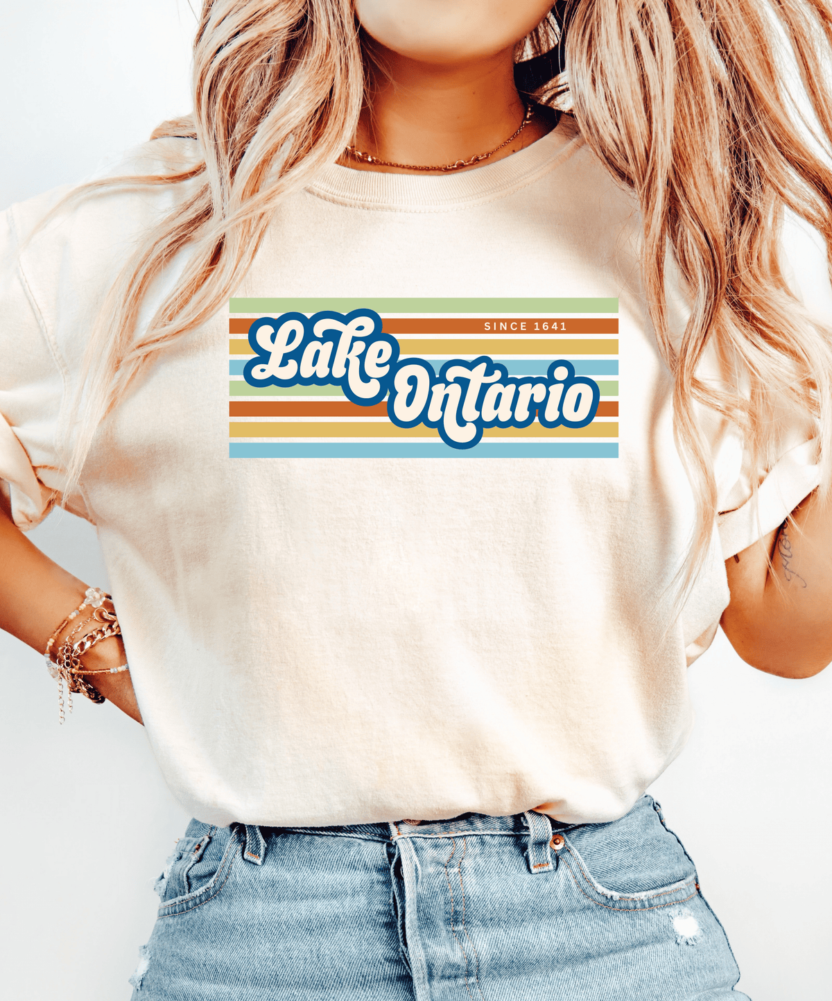 A woman wearing a cream-colored t-shirt with a retro-style graphic that reads &