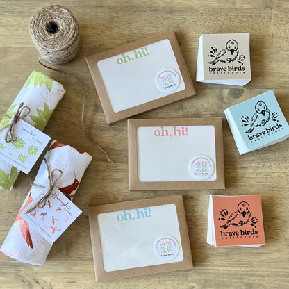 3 boxes of letterpress notecards, styled with Brave Birds stickers and tea towels
