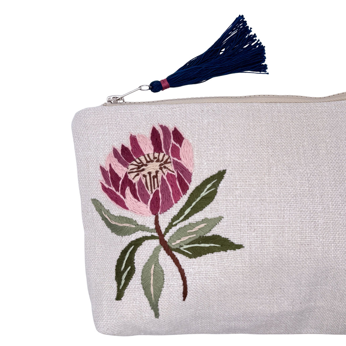 Handmade Unique embroidered protea flower featuring various shades of blush pink and mauve with green leaves on the stem, pouch on linen with blue tassel zipper closure, close up