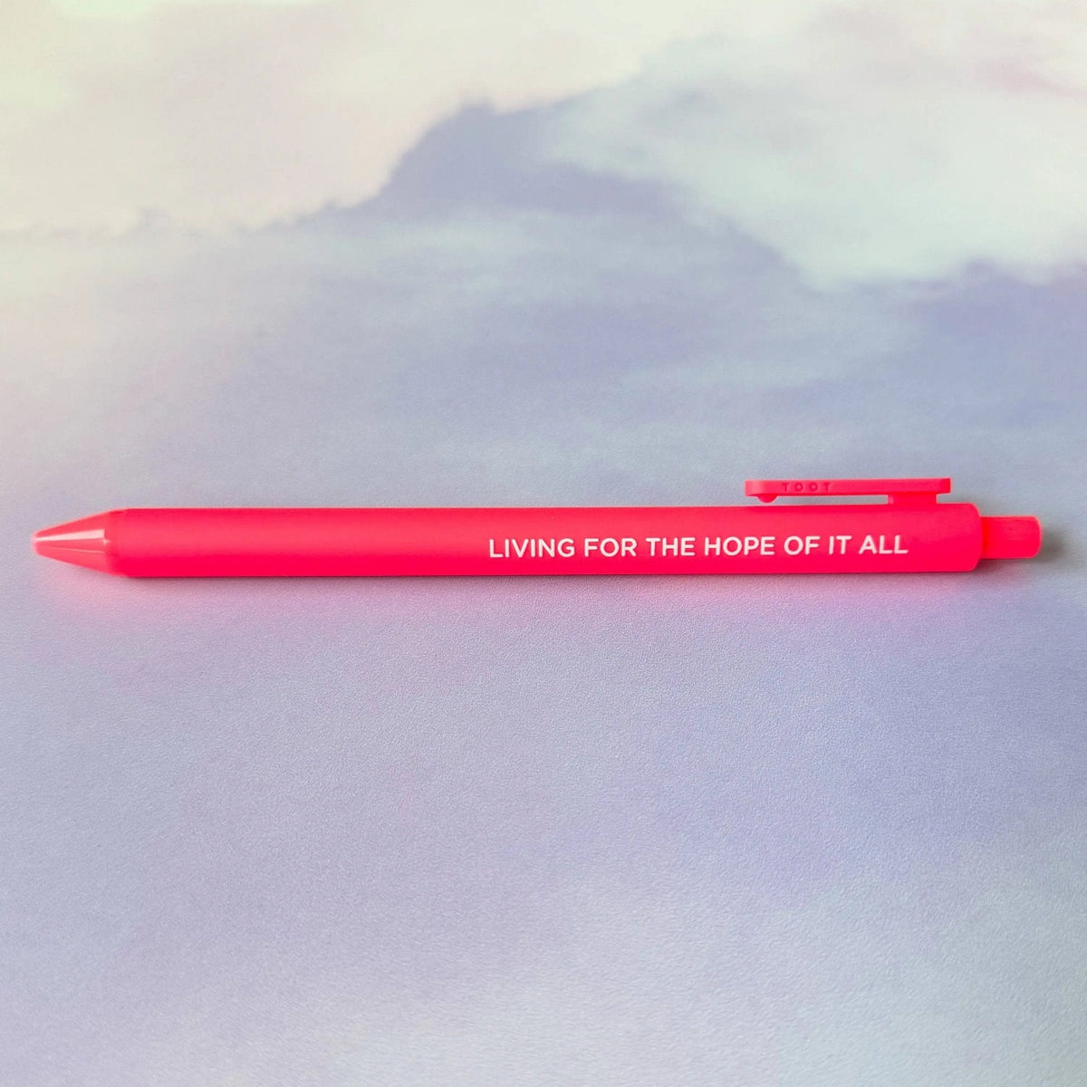 Living For the Hope of it All jotter gel pen flat lay — neon coral barrel folklore era desk pen by indie artist MangoIllustrated