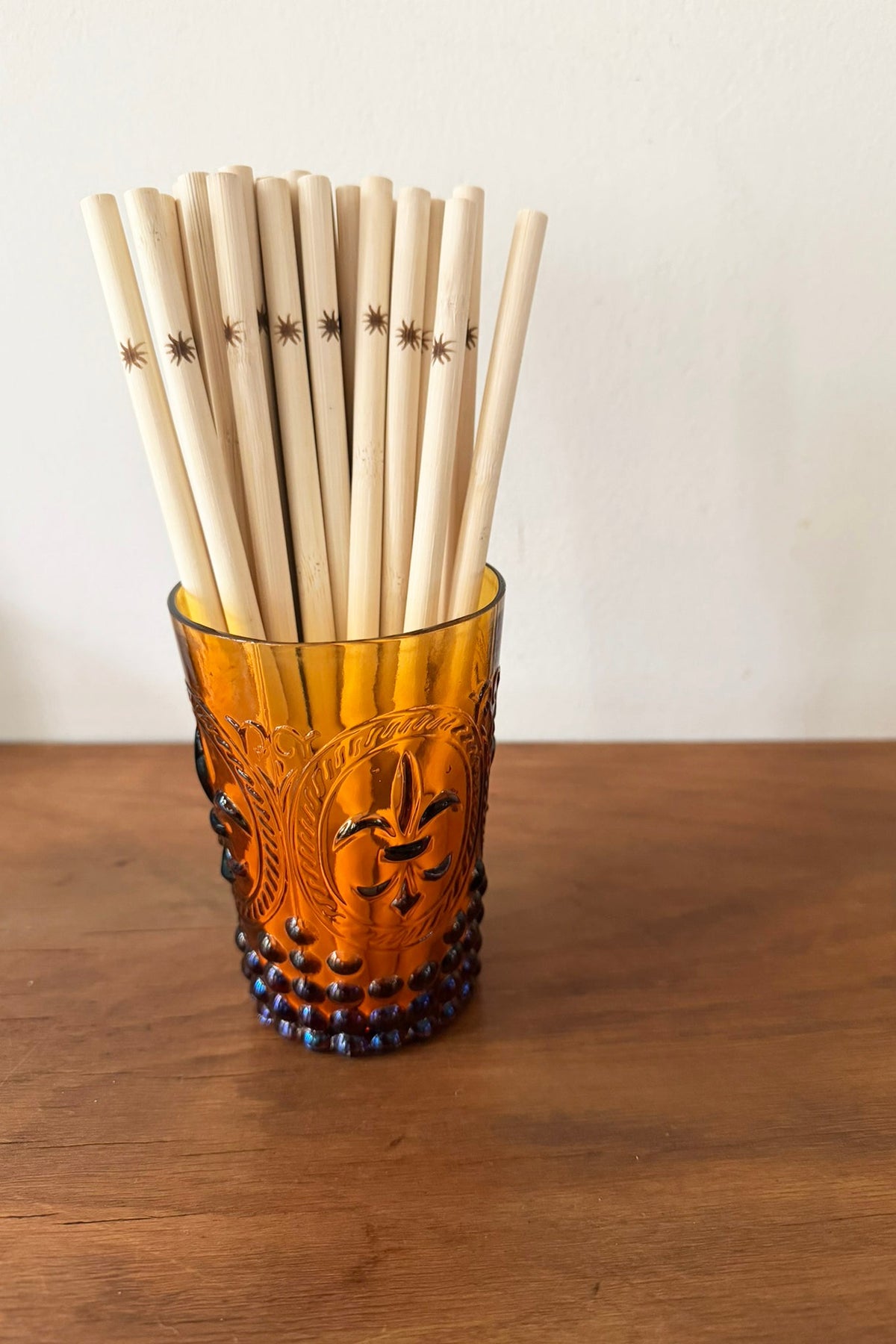 Vintage-style glass filled with bamboo straws on a wooden surface