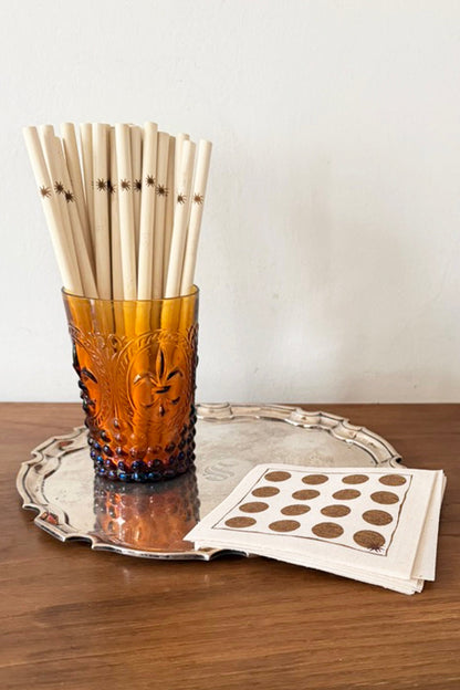 Amber glass with bamboo straws on a silver tray with a white napkin