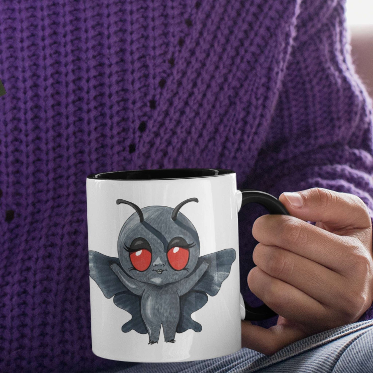 Person in a purple sweater holding the cute Mothman cryptid coffee mug