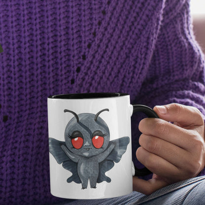 Person in a purple sweater holding the cute Mothman cryptid coffee mug