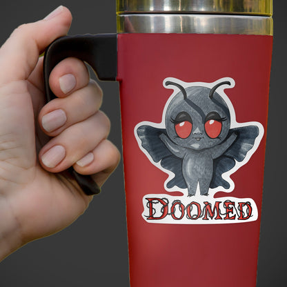 Mothman cryptid sticker on a red insulated travel mug held in one hand